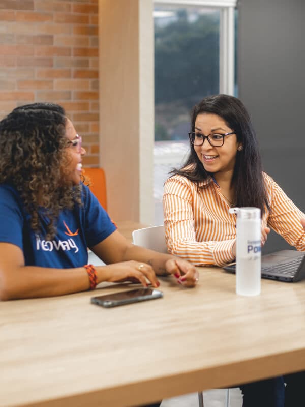 Duas mulheres funcionárias da Neoway conversando sobre a história da empresa.