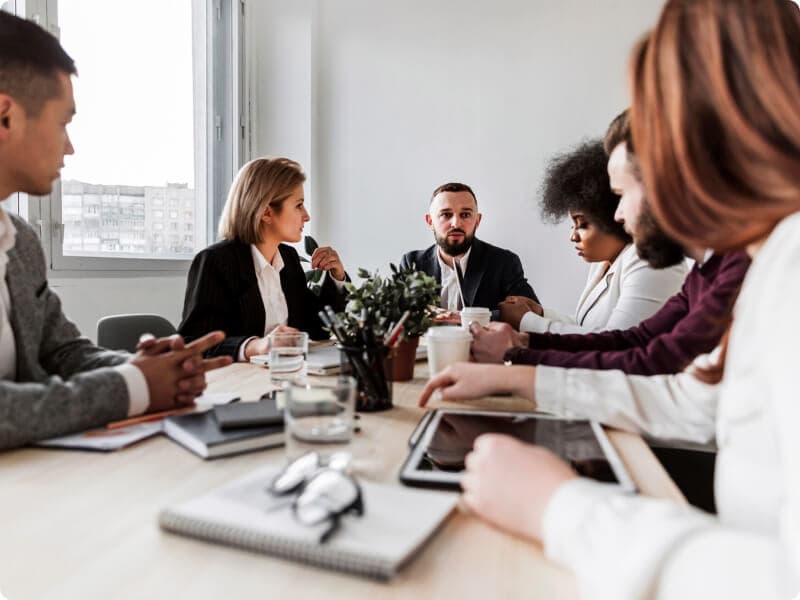 Três homens e três mulheres conversam sobre governança corporativa em uma sala de reunião.