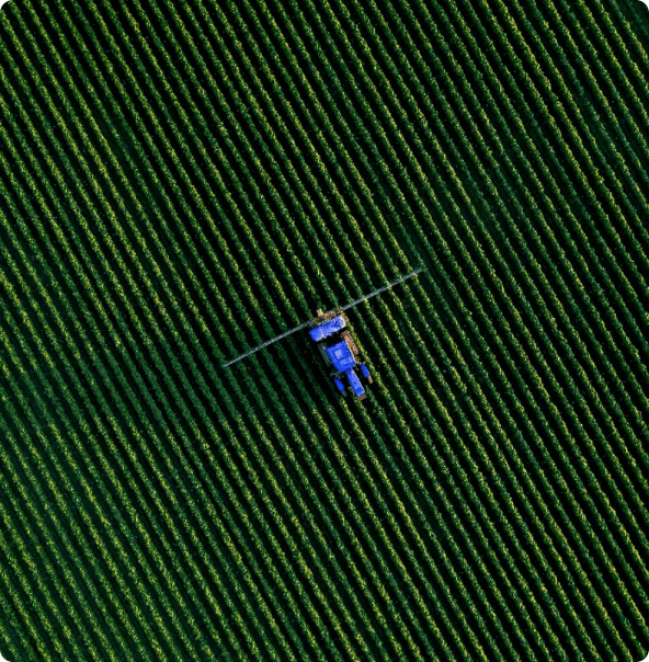 Campo bem verde com uma máquina agrícola passando, como se estivesse arando o pasto.