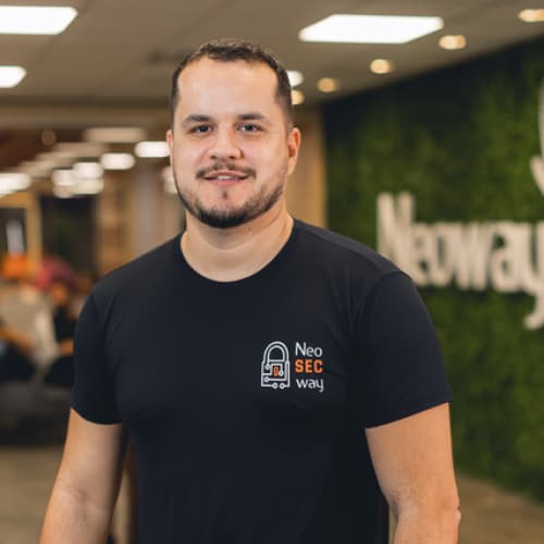 Flávio Costa, CISO da Neoway, homem branco com cabelo e barba escuros, camisa preta, olhando para frente de maneira sorridente.