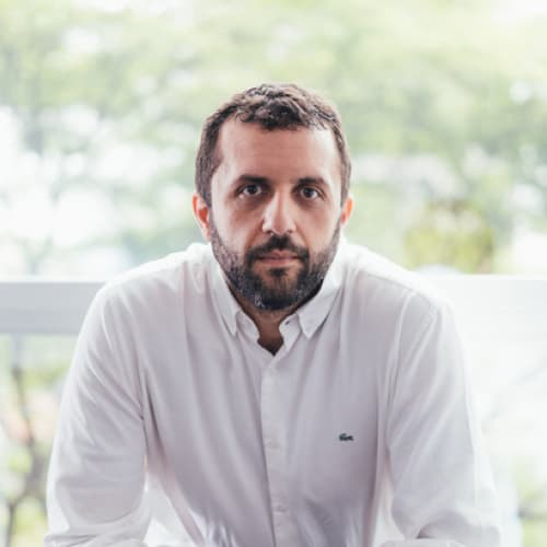 Rodrigo Barcia, CEO da Neoway, homem branco com cabelo e barba escuros, camisa branca, olhando para frente de maneira séria.