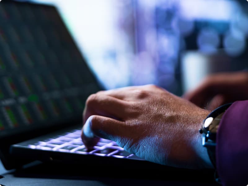 Mãos de um homem digitando no teclado de um notebook.