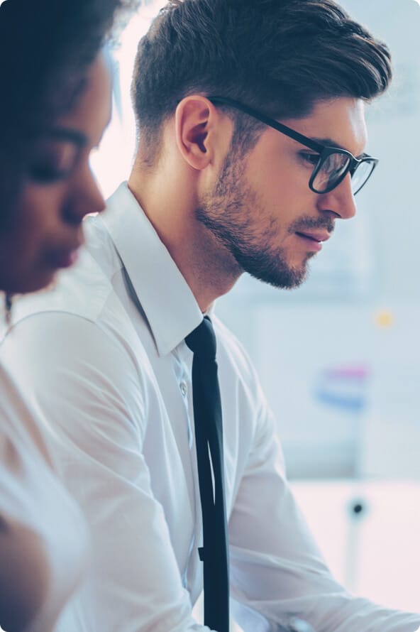 Homem branco e mulher negra analisam dados do mercado de capitais com DataWise + em uma aparente reunião de negócios.