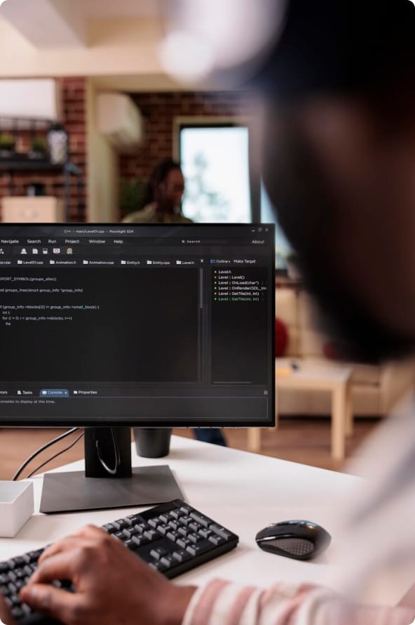 Um homem digita no teclado de um computador enquanto observa a tela do monitor com várias informações e dados corporativos.