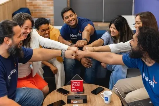 Colaboradores da Neoway, uma empresa B3 Homens e mulheres funcionários da Neoway estão reunidos e dando as mãos com os punhos fechados, demonstrando o espírito colaborativo do time.