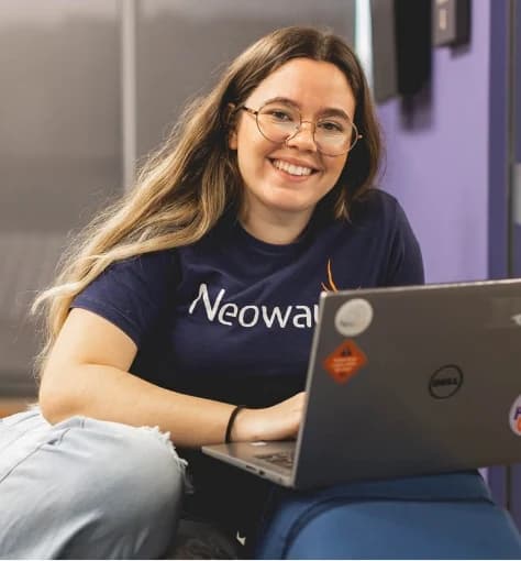 Colaboradora da Neoway Mulher branca de óculos com um notebook no colo para apresentar os combustíveis da Neoway, atrelado ao manifesto da empresa.